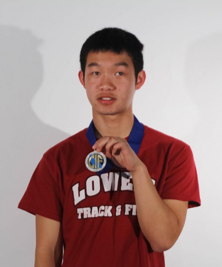 Junior Ethan Fung, in his Cardinal-spirited Track & Field shirt, proudly holds
his medal in front of his chest.