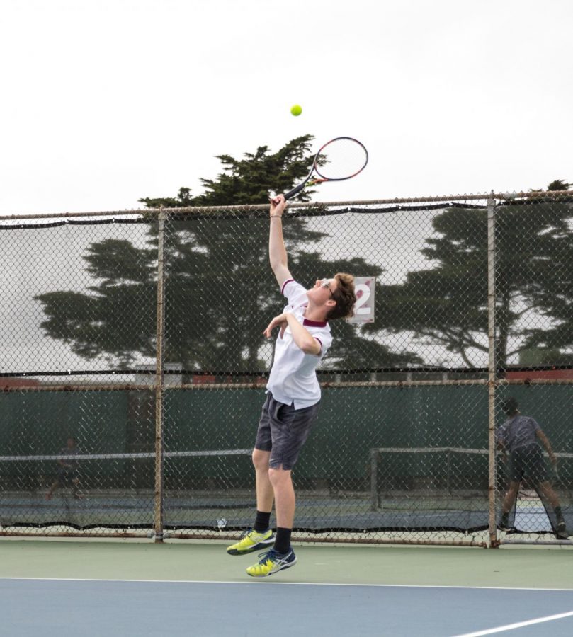 Senior co-captain Nick Morgenstein serves the ball after blessing the tennis court using Virgin Mary candles.