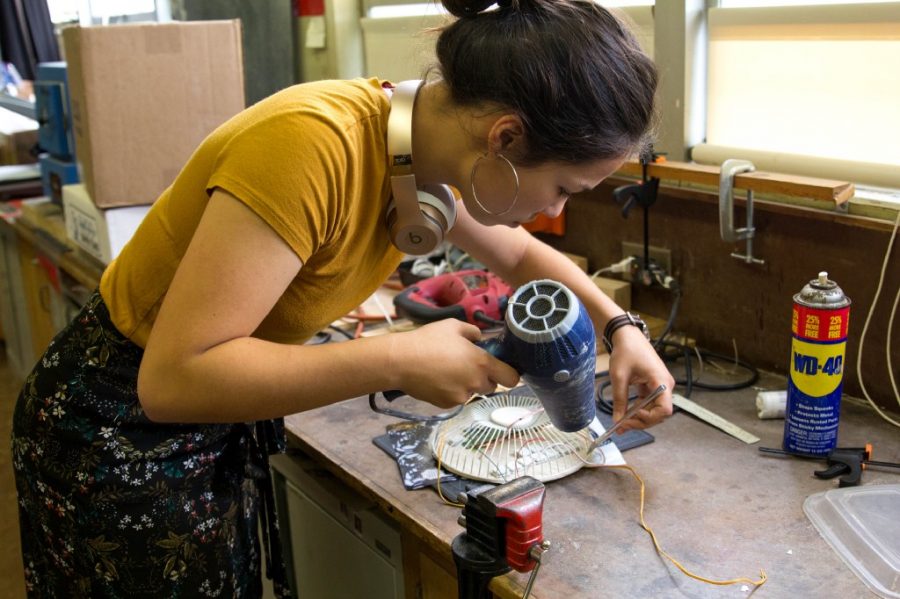 Junior Abigail Falk works on a wearable sculpture made of discarded electronics.